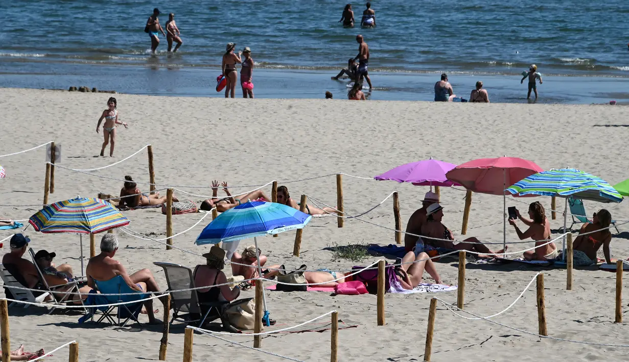 Orang-orang menikmati sore dengan area terpisah untuk mematuhi jaga jarak di pantai "Plage du Couchant" di La Grande-Motte, Prancis Selatan, Selasa (26/5/2020). Area pemisah itu berupa kotak-kotak yang dibatasi dengan tali yang masing-masing berjarak 2 meter antar satu sama lain. (Pascal GUYOT/AFP)
