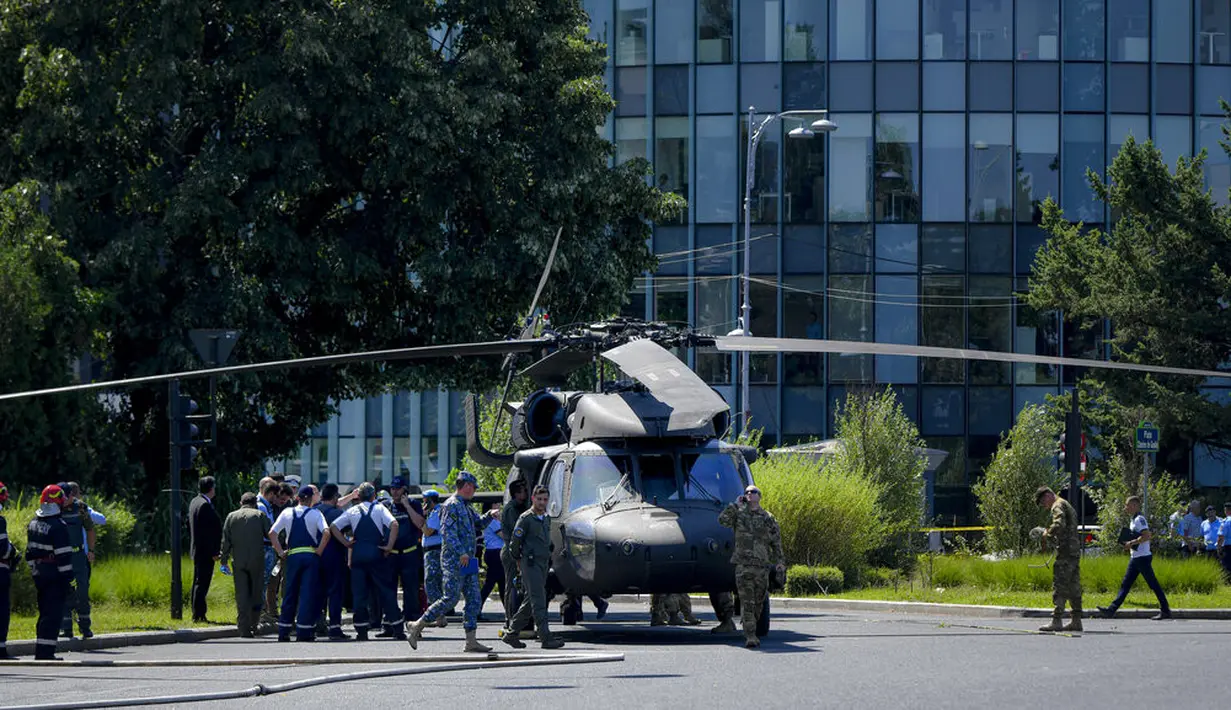 Prajurit berjalan dengan helikopter Black Hawk militer AS setelah mendarat darurat di boulevard yang sibuk, di Bucharest, Rumania, Kamis (15/7/2201). Pendaratan itu merusak dua mobil setelah merobohkan dua tiang lampu namun tidak ada korban yang dilaporkan. (AP Photo/Andreea Alexandru)