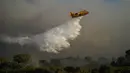 Sebuah pesawat pembuangan air membuang air ke api di dekat Le Luc, Prancis selatan, Selasa (17/8/2021). Kebakaran hutan mengirimkan asap yang mengepul menuruni lereng berhutan menuju kebun anggur di daerah yang indah. (AP Photo/Daniel Cole)