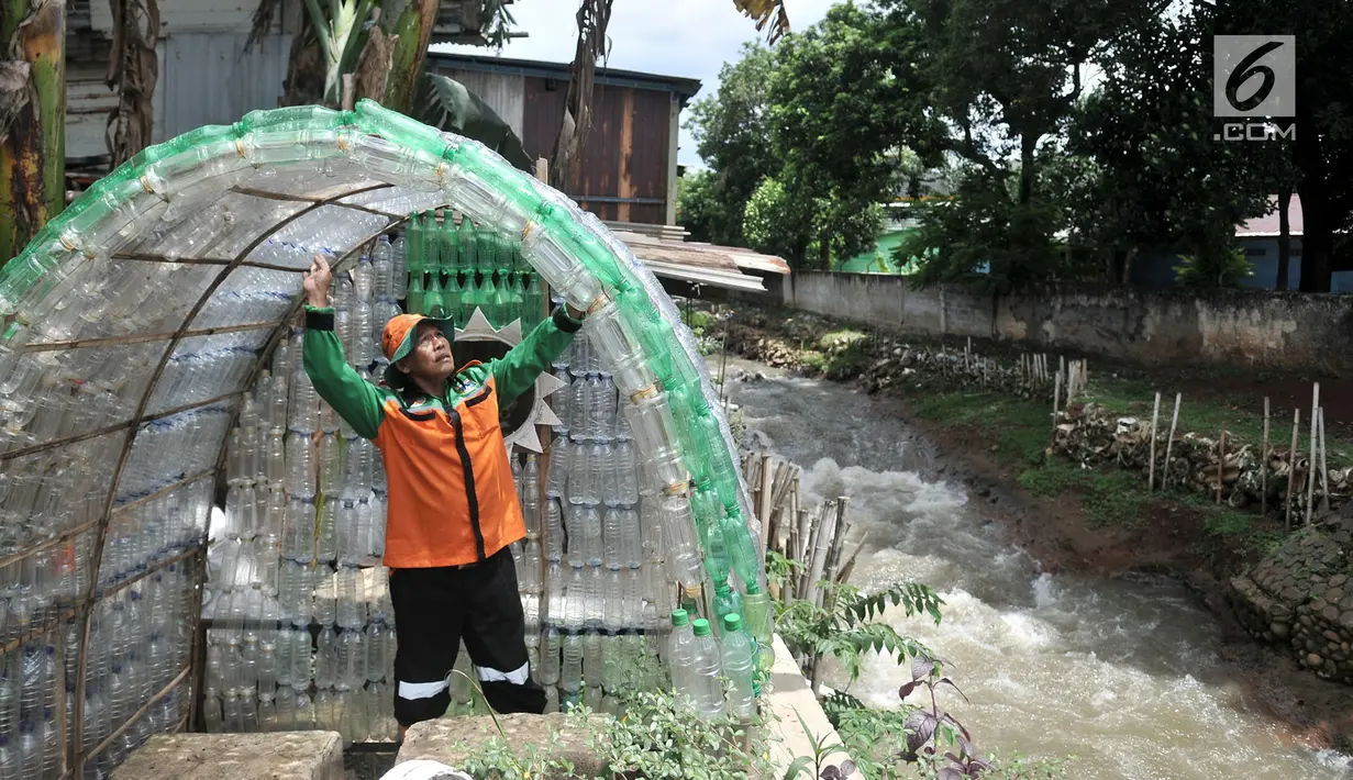 Petugas UPK Badan Air DLH DKI Jakarta saat merapikan instalasi botol yang menghiasi pos di Pasar Rebo, Jakarta, Selasa (12/3). Lebih dari seribu botol plastik bekas dipasang untuk menghiasi Pos  UPK Badan Air di Pasar Rebo. (merdeka.com/Iqbal Nugroho)