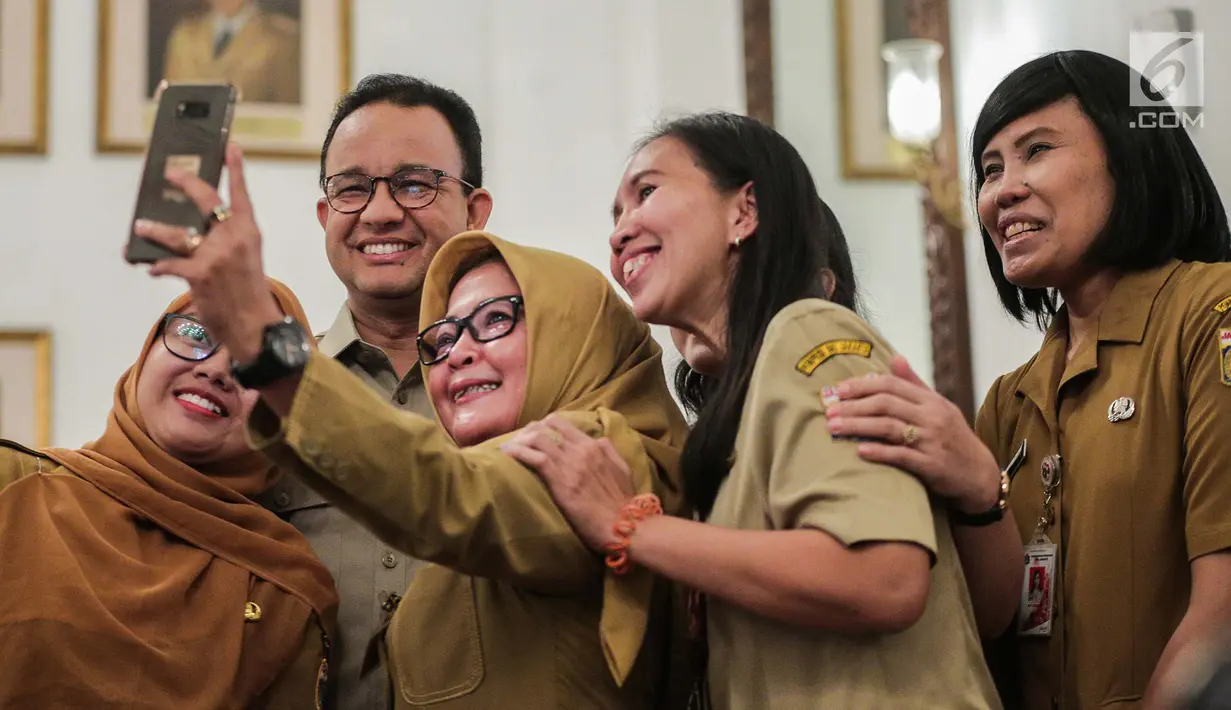 Gubernur DKI Jakarta Anies Baswedan berselfie dengan pegawai Pemprov saat menggelar halal bihalal di Balaikota, Jakarta, Senin (10/6/2019). Pemerintah Provinsi DKI Jakarta menggelar Halal Bihalal pada hari pertama PNS masuk kerja setelah libur Lebaran 2019. (Liputan6.com/Faizal Fanani)