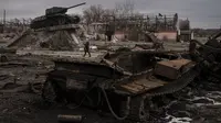 Seorang perempuan berjalan melewati tank yang hancur di kota Trostyanets, Ukraina, Senin, 28 Maret 2022. Trostsyanets baru-baru ini direbut kembali oleh pasukan Ukraina setelah dikuasai oleh Rusia sejak awal perang. (AP Photo/Felipe Dana)