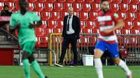 Pelatih Real Madrid, Zinedine Zidane (tengah) melihat pemainnya bertanding melawan Granada pada pertandingan lanjutan La Liga Spanyol  di stadion Nuevo Los Carmenes di Granada (13/7/2020). Madrid menang tipis 2-1 atas Granada. (AFP/Jorge Guerrero)