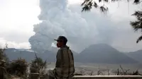 Seorang warga setempat duduk di bangku kayu sambil melihat Gunung Bromo yang sedang erupsi di Ngadisari, Probolinggo, Jawa Timur, Selasa (5/1/2016). (REUTERS/Darren Whiteside)