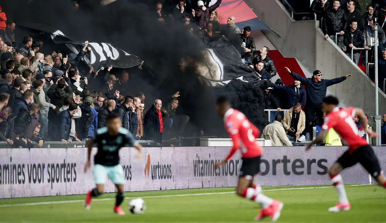 Asap hitam menyelimuti tribun penonton saat pertandingan sepak bola PSV Eindhoven vs Ajax di Stadion Philips, Belanda (23/4). Akibat asap itu beberapa penonton mengalami gangguan pernapasan dan mata. (Olaf KRAAK / ANP / AFP)