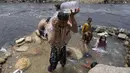 <p>Orang-orang mendinginkan diri di sungai saat suhu mencapai 35 C (95 F) di Karachi, Pakistan, 13 Juli 2023. (AP Photo/Fareed Khan)</p>