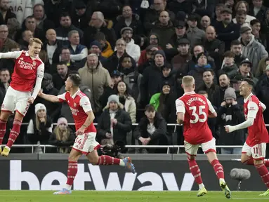 Gelandang Arsenal, Martin Odegaard (kiri) berselebrasi usai mencetak gol ke gawang Tottenham Hotspur pada pertandingan lanjutan Liga Inggris di Stadion Tottenham Hotspur di London, Inggris, Minggu (15/1/2023). Arsenal menang atas Tottenham dengan skor 2-0. (AP Photo/Frank Augstein)