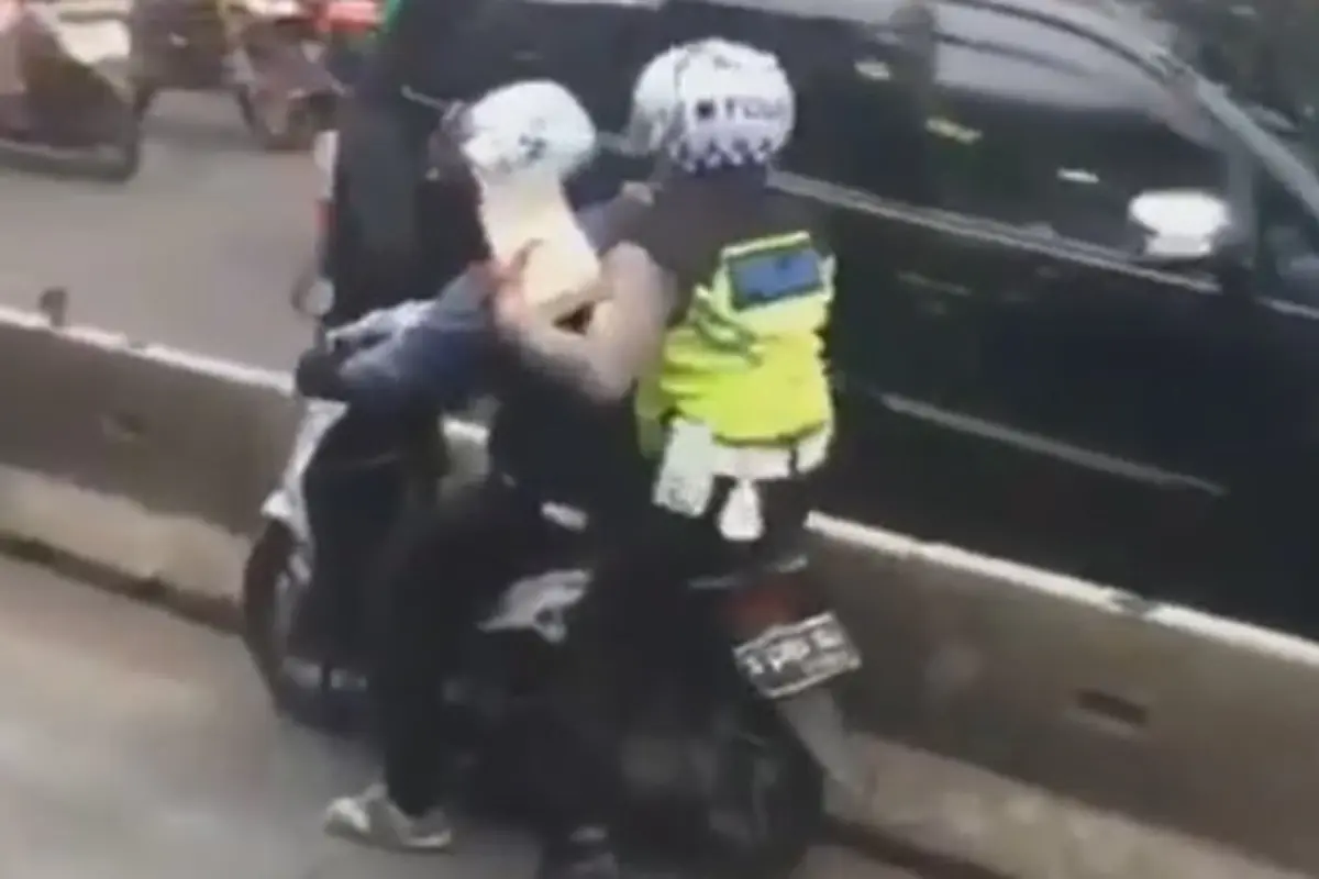 seorang pemotor berupaya menghindari penilangan yang dilakukan polisi saat masuk jalur busway.