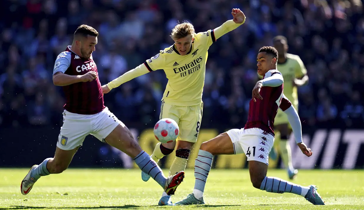 Gelandang Arsenal, Martin Odegaard (tengah) berusaha melewati pemain Aston Villa, Jacob Ramsey dan John McGinn pada pertandingan lanjutan Liga Inggris di Villa Park, Birmingham, Inggris, Sabtu (19/3/2022). Arsenal menang tipis atas Aston Villa 1-0. (Nick Potts/PA via AP)