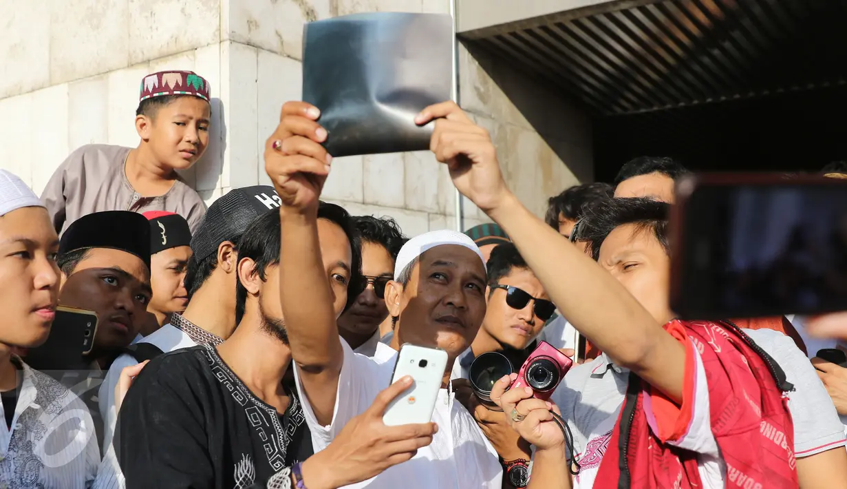 Warga menikmati proses Gerhana Matahari Total (GMT) menggunakan film bekas ronsen di halaman masjid Istiqlal seusai melakukan salat gerhana, Jakarta, Rabu (9/3/2016). (Herman Zakharia) 