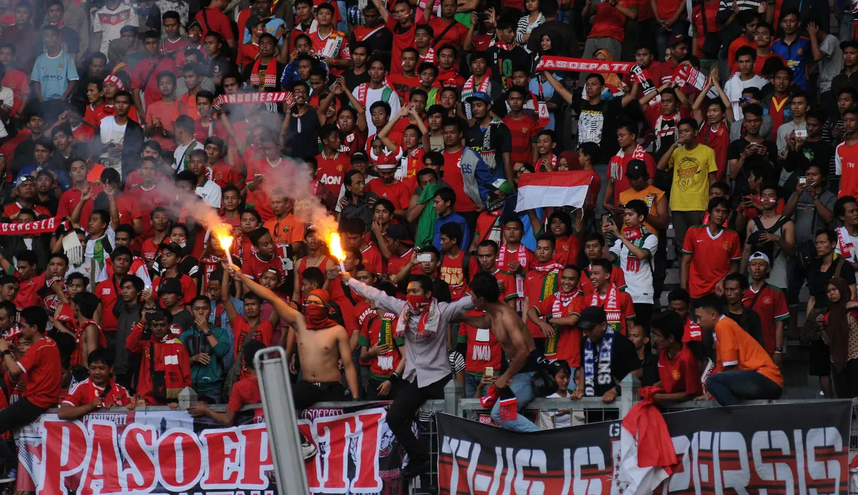 Sejumlah supporter timnas Indonesia menyalakan flare merayakan kemenangan Garuda Muda atas Brunei Darussalam 2-0 di kualifikasi Piala Asia 2016 di Stadion GBK Jakarta, Minggu (29/3/2015). (Liputan6.com/Helmi Fithriansyah)
