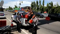Polisi menurunkan pembatas jalan dari mobil saat melakukan sistem buka tutup jalan menuju Pelabuhan Merak, Cilegon, Banten, Jumat (29/4/2022). Sistem buka tutup tersebut membuat kemacetan panjang hingga ke dalam Tol Tangerang-Merak. (Liputan6.com/Angga Yuniar)