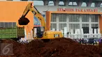 Alat berat melakukan proses pengerukan tanah di luar Stadion Pakansari, Kabupaten Bogor, Minggu (21/8). Jelang pelaksanaan PON XIX Jawa Barat, pembangunan sarana pertandingan di Stadion Pakansari terus dikerjakan. (Liputan6.com/Helmi Fithriansyah)