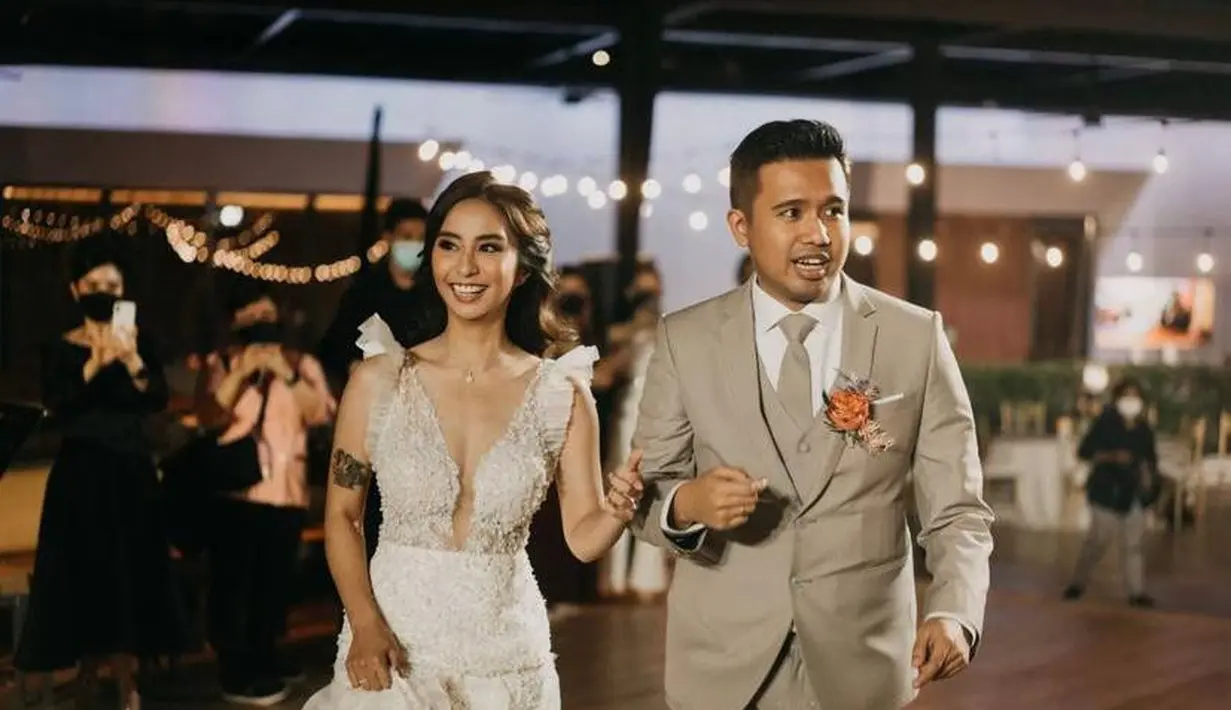 Untuk acara resepsi, Clay berganti pakaian menjadi dress putih rancangan desainer Cynthia Tan. (Instagram/amoretti_awp).