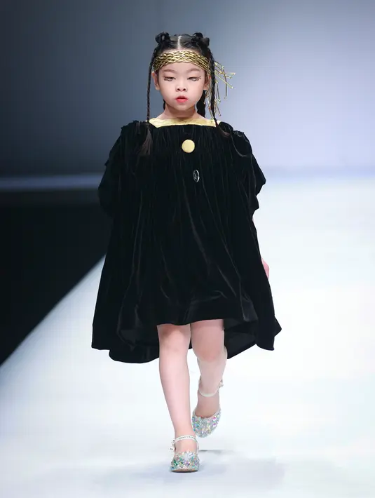 Seorang model anak membawakan koleksi busana dari KUNJIE karya Liu Shuming pada gelaran China Fashion Week di Beijing, China, Selasa (27/10/2020). (STR / AFP)