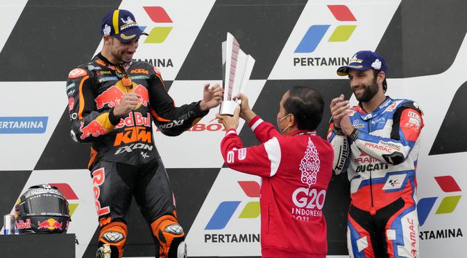 Presiden RI, Joko Widodo menyerahkan langsung trofi kepada pembalap KTM, Miguel Oliveira, yang naik podium MotoGP Mandalika di Sirkuit Mandalika, Lombok, Minggu (20/03/2022). (AP Photo/Achmad Ibrahim)