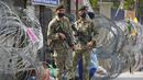 Tentara bersenjata berjaga di samping kawat berduri di kawasan Segambut Dalam yang ditempatkan di bawah perintah peningkatan kontrol gerakan (EMCO) karena peningkatan drastis jumlah kasus COVID-19 yang tercatat selama 10 hari terakhir di Kuala Lumpur, Malaysia, Minggu (27/6/2021). (AP Photo/Vincent