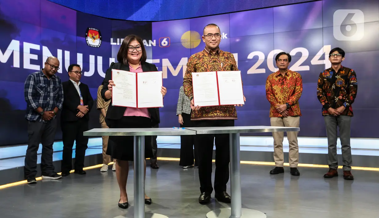 Ketua Komisi Pemilihan Umum (KPU) Hasyim Asy'ari (tengah kanan) bersama CFO KLY Octaviany Sarimawan (tengah kiri) menunjukkan dokumen kerja sama saat acara penandatanganan MoU antara Emtek dengan KPU di SCTV Tower, Jakarta, Selasa (30/8/2022). Kerja sama KPU dengan Emtek ini terkait sosialisasi Pemilihan Umum yang akan diselenggarakan 2024 mendatang. (Liputan6.com/Johan Tallo)