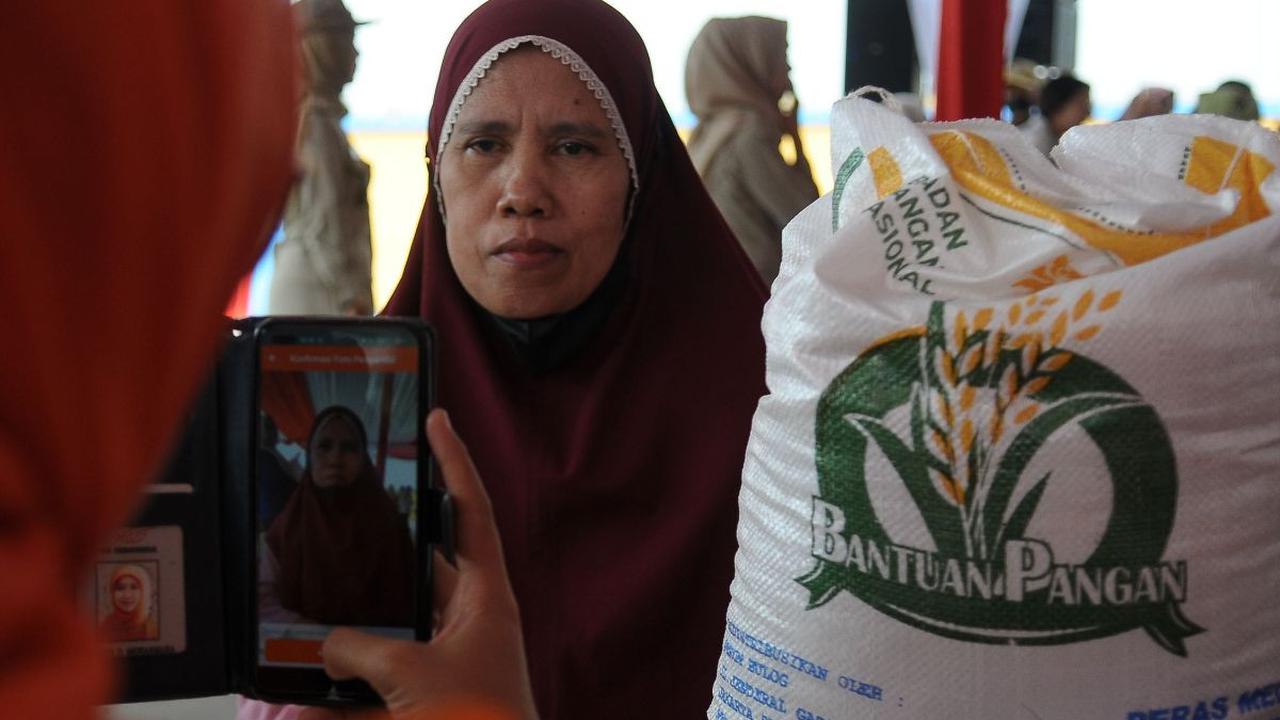 Petugas mengambil gambar seorang warga saat menerima bantuan pangan 10 kilogram beras di Gudang Bulog, Jakarta, Senin (11/9/2023).