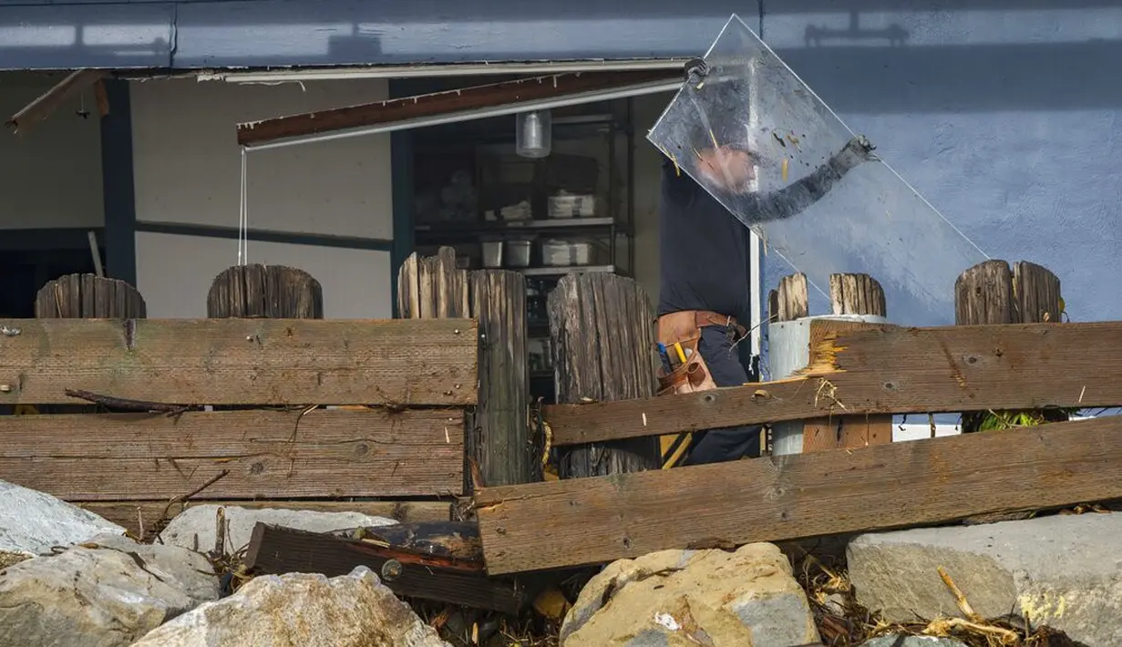 Seorang pria membersihkan puing-puing dari Zelda's on the Beach setelah restorannya rusak akibat badai di Capitola, California, Kamis (5/1/2023). Angin topan yang merusak, ombak bergelombang dan hujan lebat dari "sungai atmosfer" yang kuat menghantam California pada hari Kamis, melumpuhkan listrik hingga puluhan ribu, menyebabkan banjir. (AP Photo/Nic Coury)
