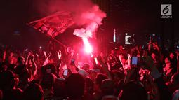 Suporter tim Macan Kemayoran menyalakan flare saat merayakan gelar juara Go-Jek Liga 1 Indonesia 2018 bersama Bukalapak yang diraih Persija di kawasan Bundaran HI, Jakarta, Minggu (9/12). Persija juara dengan 62 poin. (Liputan6.com/Helmi Fithriansyah)