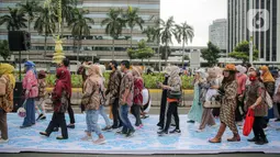 Sejumlah orang yang mengenakan batik berjalan di catwalk sepanjang Jalan Jenderal Sudirman, Jakarta, Minggu (2/10/2022). Kegiatan yang diikuti ratusan orang ini diselenggarakan oleh Bank Mandiri untuk menyambut Hari Batik Nasional yang jatuh setiap tanggal 2 Oktober 2022. (Liputan6.com/Faizal Fanani)