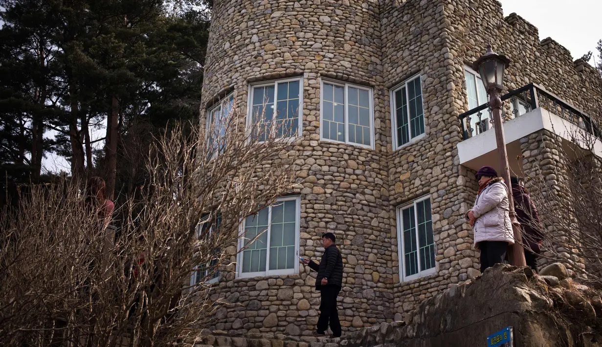 Pengunjung berdiri di luar vila yang dikenal sebagai Kastil Hwajinpodi di Pantai Hwajinpo, Korea Selatan, (19/2). Villa ini merupakan tempat liburan mendiang pendiri Korea Utara Kim Il Sung. (AP Photo/Jae C. Hong)