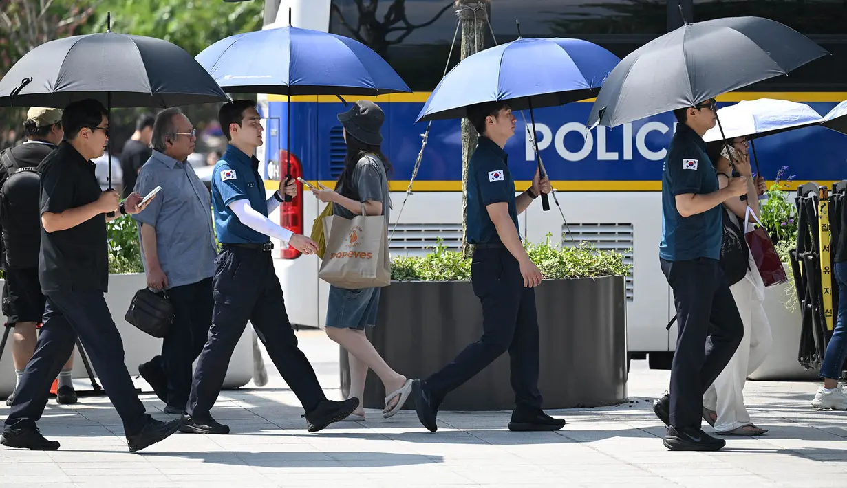 Petugas polisi menggunakan payung untuk melindungi diri dari terik matahari di sebuah jalan di Seoul,  Korea Selatan, Senin,  3 Agustus 2026. (AFP/  Jung Yeon-je)