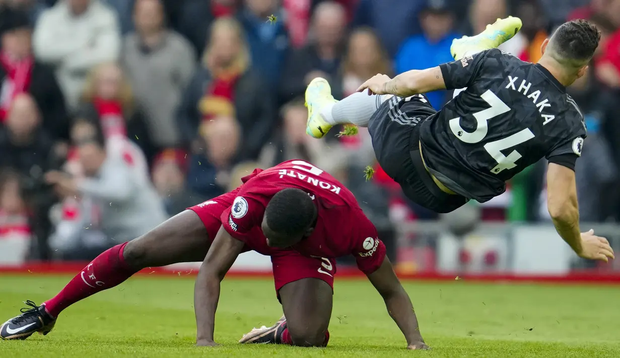 Gelandang Arsenal, Granit Xhaka (kanan) terjatuh saat perebutan bola dengan bek Liverpool, Ibrahima Konate pada laga lanjutan pekan ke-30 Liga Inggris 2022/2023 di Anfield Stadium, Liverpool, Minggu (9/4/2023) malam WIB. (AP Photo/Jon Super)