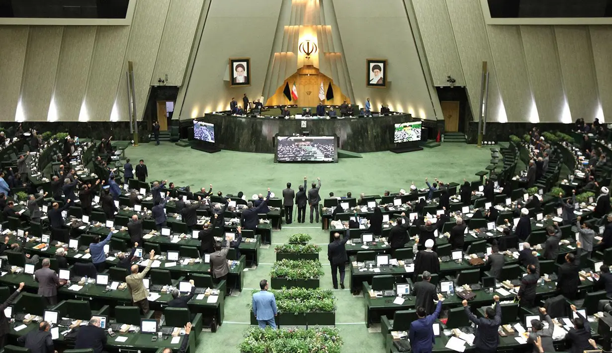 Anggota parlemen Iran mengangkat tangan saat voting RUU yang menetapkan pasukan militer Amerika Serikat sebagai teroris, Teheran, Selasa (7/1/2020). Dalam RUU itu seluruh pasukan militer AS serta pihak terkait pembunuhan Jenderal Qasem Soleimani ditetapkan sebagai teroris. (ICANA NEWS AGENCY/AFP)