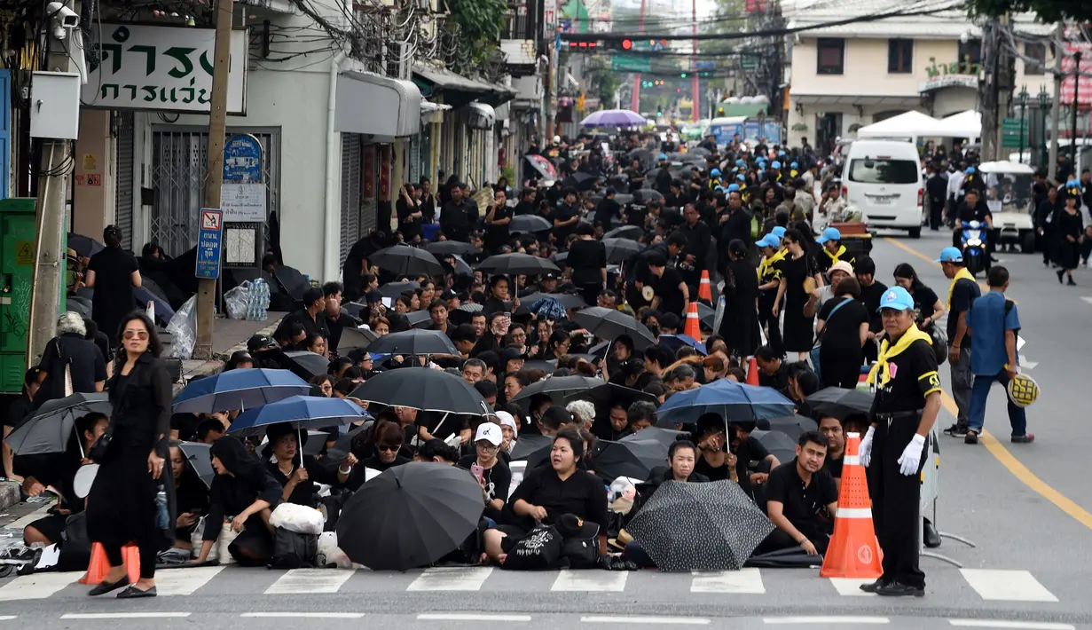 Sejumlah warga mengenakan pakaian hitam memadati jalan saat saat menunggu pemakaman mendiang Raja Thailand Bhumibol Adulyadej di Bangkok (25/10). (AFP Photo/Roberto Schmidt)