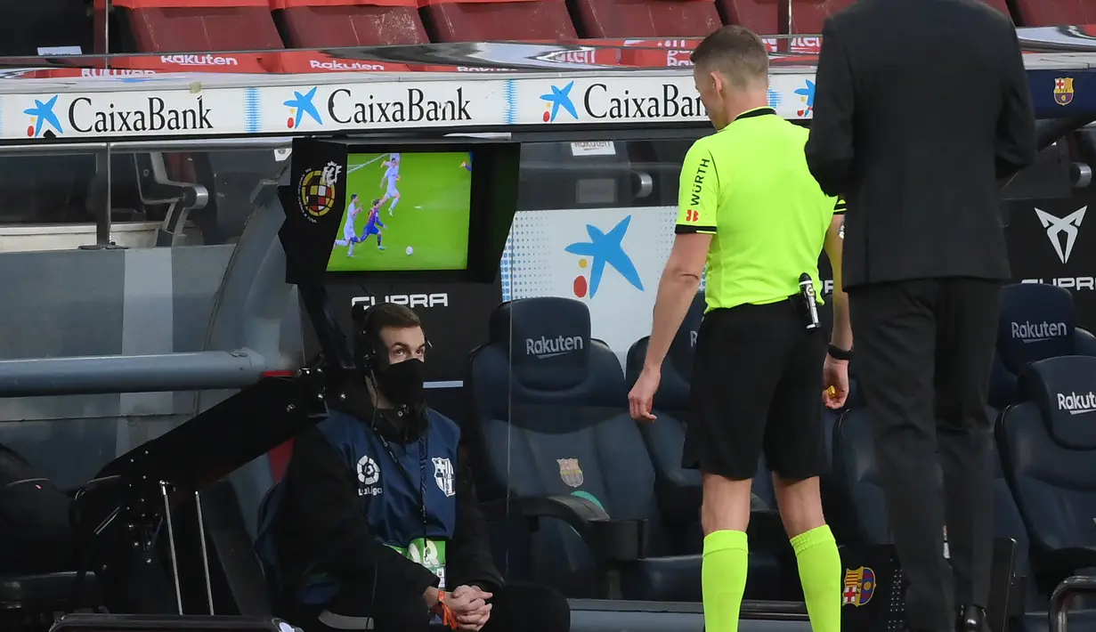 Wasit Alejandro Hernandez Fernandez memeriksa rekaman VAR yang menghasilkan tendangan penalti untuk Barcelona, dalam laga lanjutan Liga Spanyol 2020/21 antara Barcelona melawan Valencia di Camp Nou Stadium, Barcelona, Sabtu (19/12/2020). Barcelona bermain imbang 2-2 dengan Valencia. (AFP/Lluis Gene)