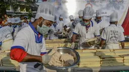 Pembuat roti dan koki menyiapkan kue sepanjang 6,5 km untuk kue terpanjang dunia, di Thrissur di negara bagian Kerala, India selatan (15/1/2020). Sebelumnya rekor Guinness World Record untuk kue terpanjang diraih di China degan panjang 3,2 kilometer. (AFP/Arun Sankar)