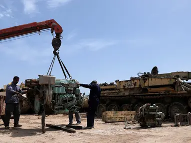 Teknisi militer Pasukan Mobilisasi Populer Irak (Hashid Shaabi) memperbaiki mesin tank di sebuah bengkel di Kerbala, Irak (7/5). Bengkel yang terletak di Kerbala ini menjadi lokasi perbaikan kendaraan-kendaraan militer rusak usai dipergunakan untuk perang. (Reuters/Abdullah Dhiaa Al- Dien)