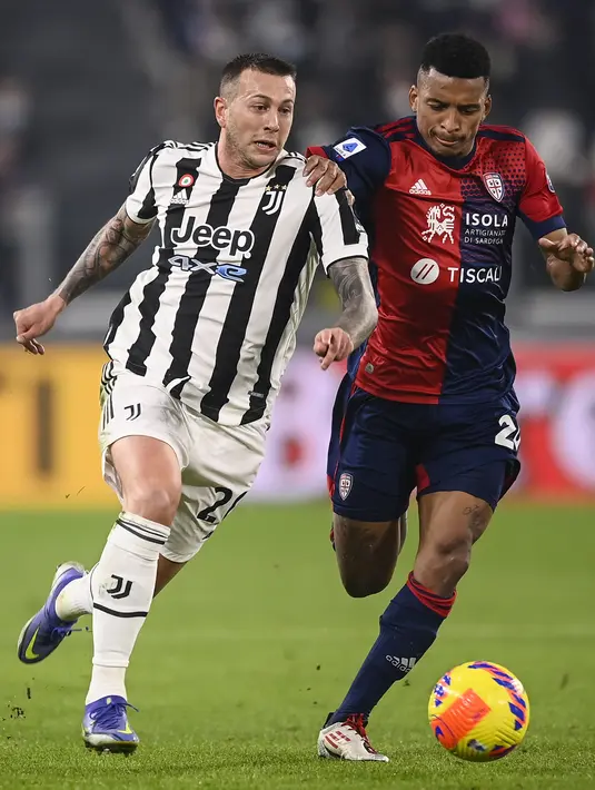Gelandang Juventus, Federico Bernardeschi membawa bola dari kejaran pemain Cagliari, Charalampos Lykogiannis pada pertandingan Liga Serie A Italia di Stadion Allianz, Turin, Rabu (22/12/2021). Juventus kini berada di posisi kelima klasemen Serie A dengan 34 poin. (Fabio Ferrari/LaPresse via AP)