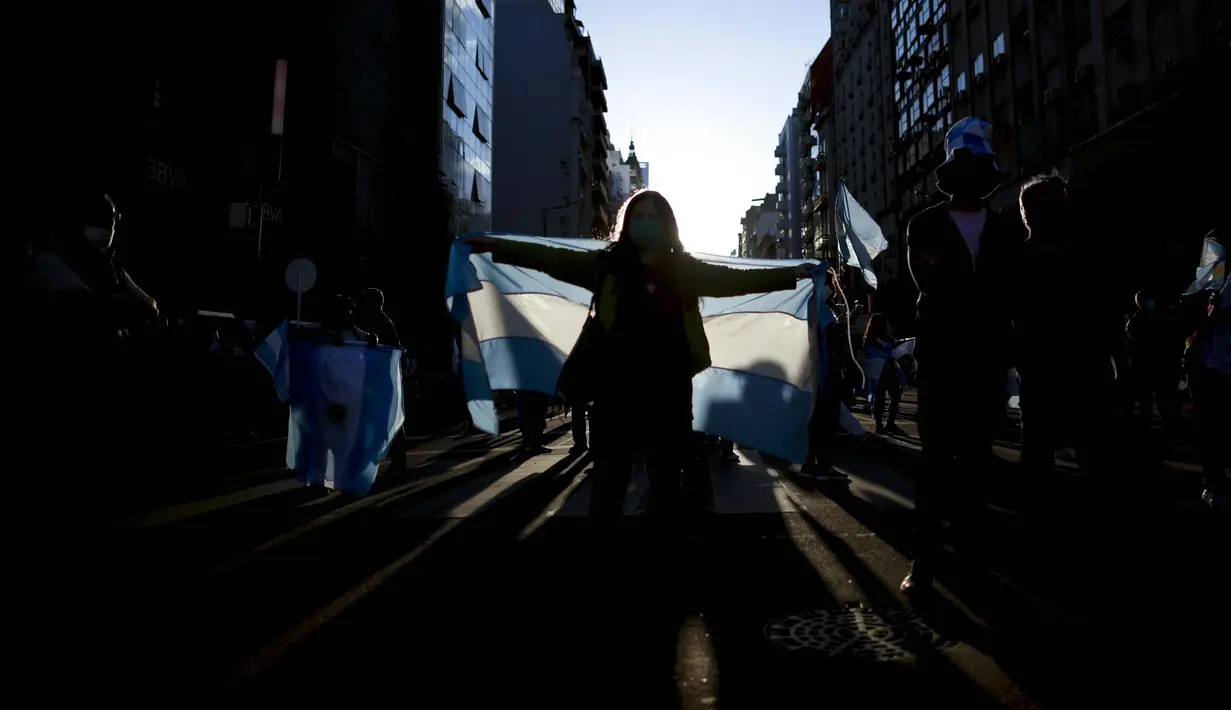 Seorang wanita memegang bendera Argentina selama protes terhadap berbagai masalah termasuk kebijakan ekonomi pemerintah dan kebijakan negara untuk memerangi penyebaran COVID-19 di Buenos Aires, Argentina, Senin (12/10/2020). (AP Photo/Natacha Pisarenko )