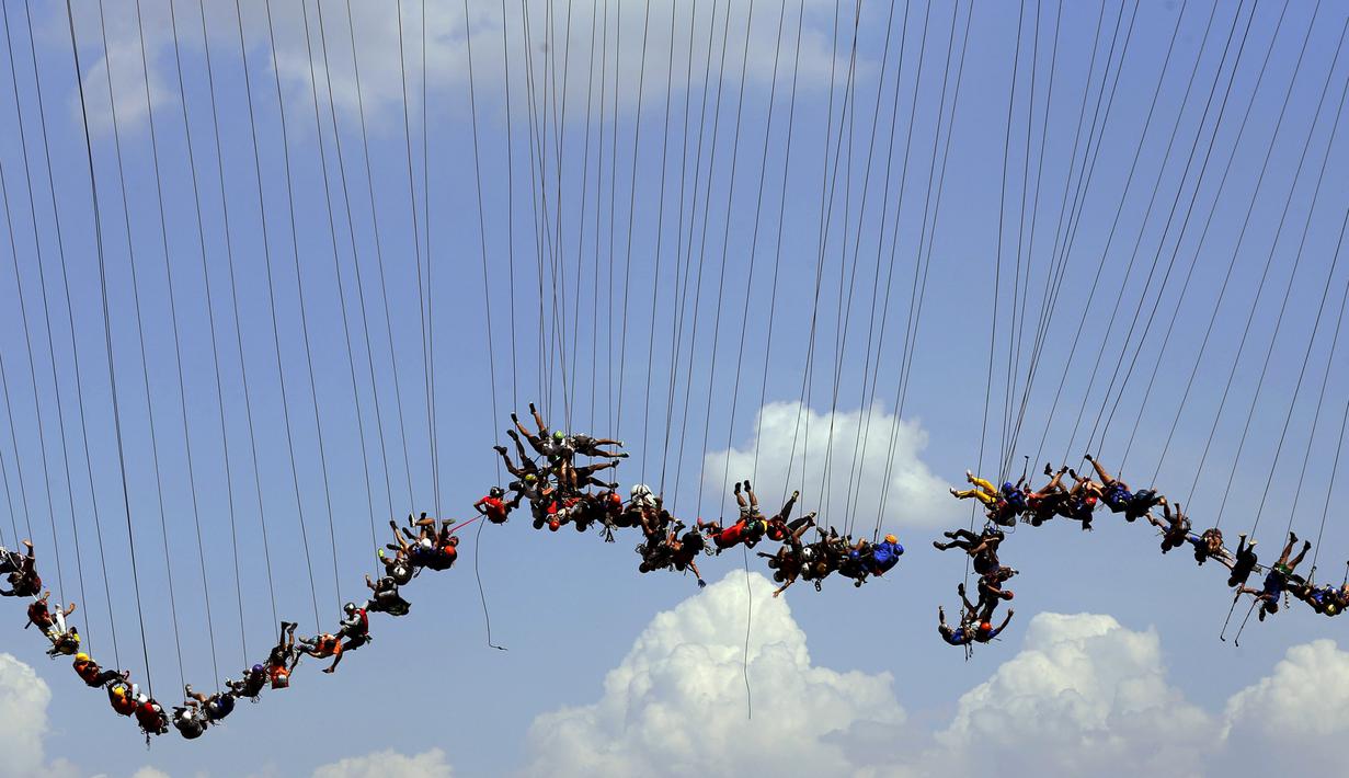 Ratusan orang bergelantung di jembatan yang memiliki ketinggian 30 meter di Hortolandia, Brasil, Minggu (10/4). Sebanyak 149 orang mencoba membuat rekor dunia dengan melompat bersama dari atas jembatan. (REUTERS/Paulo Whitaker)