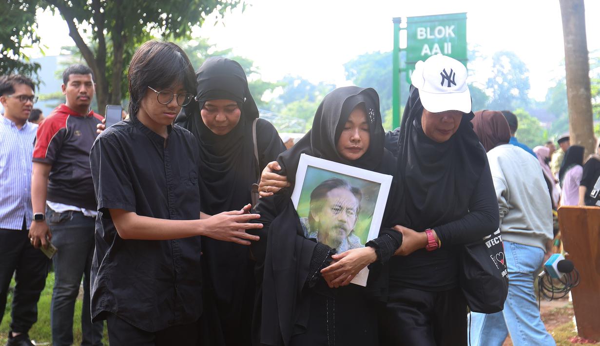 Istri Epy Kusnandar, Karina Ranau terlihat sangat terpukul saat melepas kepergian suaminya. Tampak dalam foto, Karina Ranau (kedua kanan) sesaat sebelum pemakaman suaminya, Epy Kusnandar, di Tempat Pemakaman Umum (TPU) Jeruk Purut, Jakarta Selatan, Kamis (4/12/2025) pagi. (Kapanlagi.com/Budy Santoso)