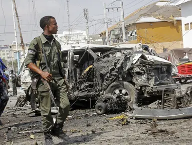 Seorang anggota pasukan keamanan berjalan melewati reruntuhan di lokasi pemboman di Mogadishu, Somalia (13/2/2021). Bom mobil meledak di Mogadishu, Somalia di luar kompleks parlemen dan tak jauh dari Istana Kepresidenan Somalia. (AP Photo/Farah Abdi Warsameh)