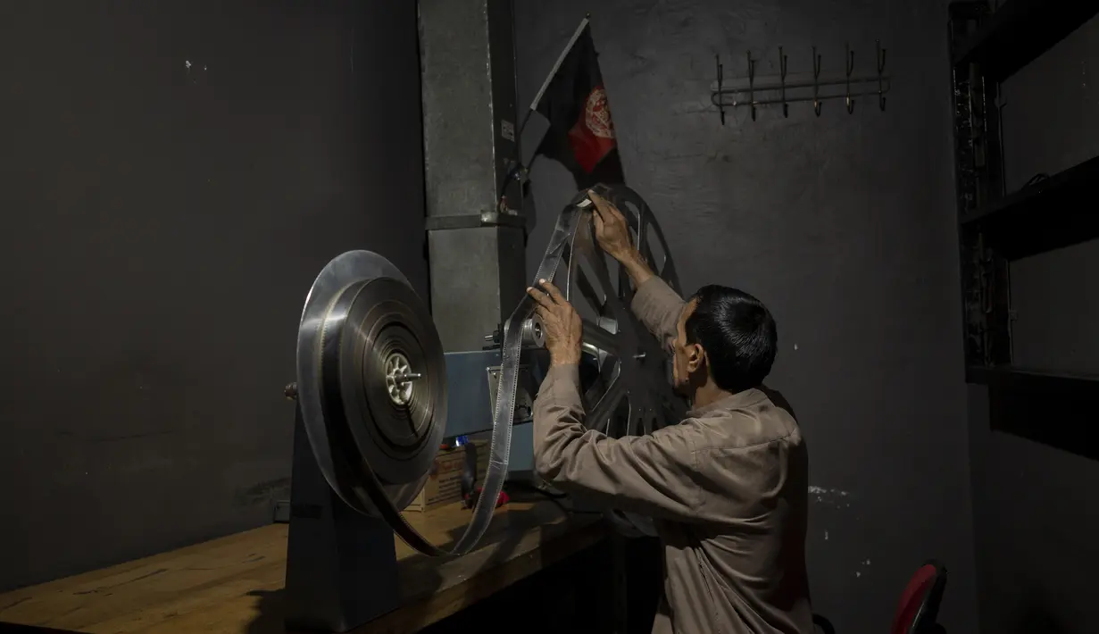Rahmatullah Ezati memutar ulang rol film di ruang proyeksi Bioskop Ariana di Kabul, Afghanistan pada 8 November 2021. Staf bioskop masih muncul di tempat kerja setiap hari berharap mereka pada akhirnya akan dibayar, meskipun ada perintah dari Taliban untuk berhenti beroperasi. (AP Photo/Bram Jansen)