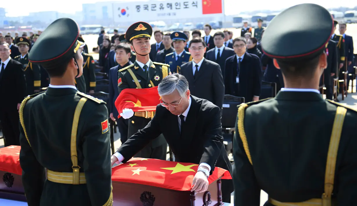 Duta Besar China untuk Korea Selatan Qiu Guohong (tengah) menempatkan bendera Chinadi atas peti mati berisi sisa-sisa tentara China yang menjadi korban dalam Perang Korea di Bandara Internasional Incheon, Seoul, Korea Selatan, Rabu (3/4). (Jung Yeon-je/Pool Photo via AP)