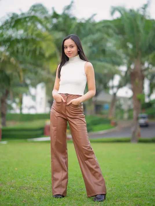 Bergaya bak model, Lyodra tampil mengenakan sleeveless turtleneck top berwarna putih yang dipadukan dengan bawahan leather pants berwarna cokelat / (instagram/lyodraofficial)