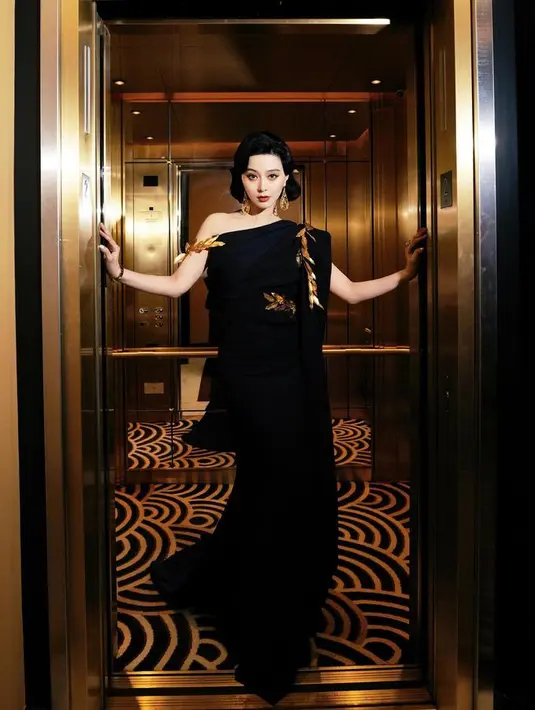 Setelah memakai gaun silver dan hijau, ia memilih ansambel hitam one shoulder. Dengan aksen emas yang mewah sebagai baju kedua. [Foto: @bingbing_fan]