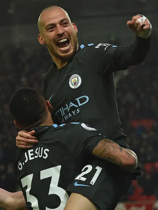 Gelandang Manchester City, David Silva melompat ke Gabriel Jesus usai mencetak gol ke gawang Stoke City pada pertandingan pekan ke-30 Premier League di bet365 Stadium, Selasa (13/3). Dua gol kemenangan Manchester City diciptakan oleh Silva (PAUL ELLI/AFP)