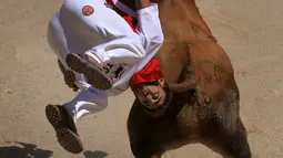 Seorang recortador melompati serudukan banteng selama Festival San Fermin di Pamplona, Spanyol, Sabtu (9/7). Aksi akrobatik melompati serangan banteng ini dinamakan recortadores. (REUTERS / Vincent West)