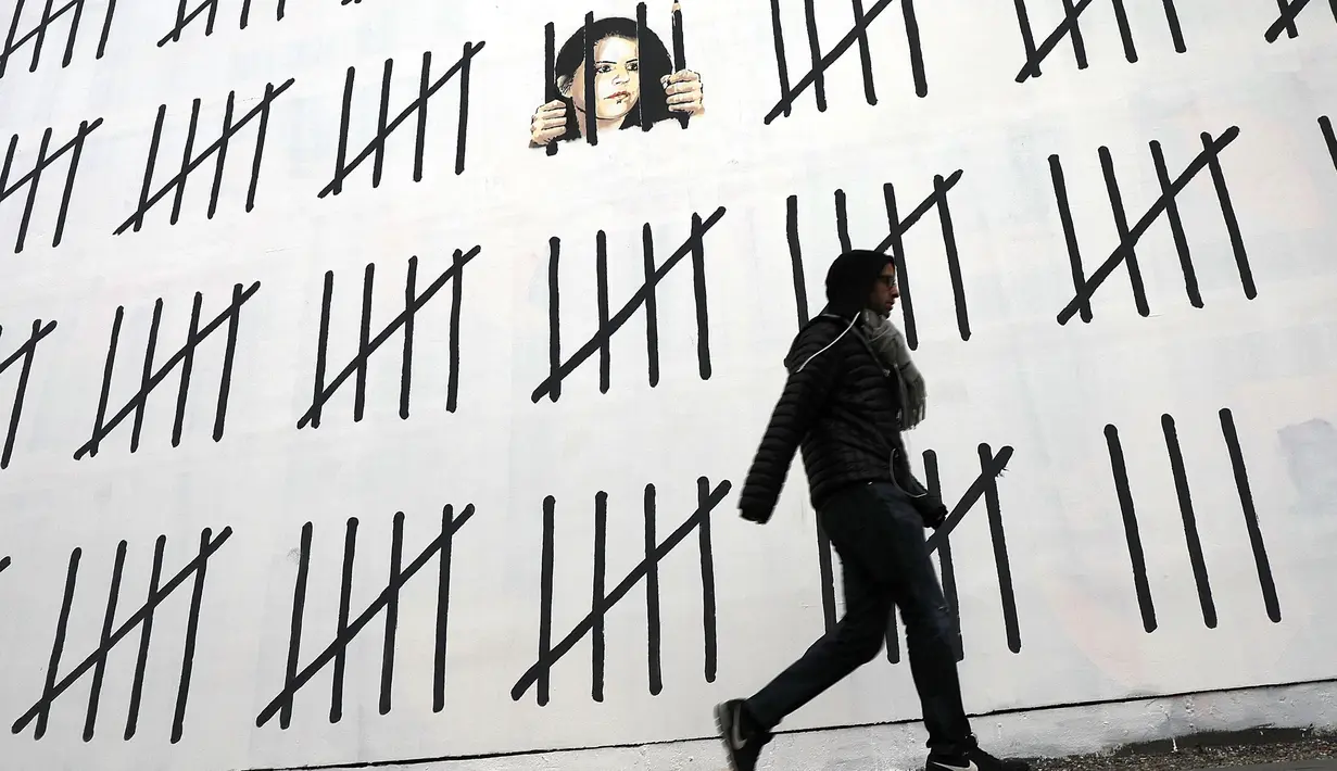 Seorang pria berjalan di sebelah tembok besar yang dimural oleh seniman Banksy di wilayah Manhattan, New York (15/3). Di bagian ujung mural tersebut, Banksy menuliskan pesan "Free Zehra Dogan". (Spencer Platt / Getty Images / AFP)