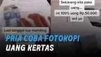 Seorang pria mencoba memfotokopi selembar uang kertas menggunakan mesin fotokopi.