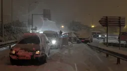 Sejumlah mobil terjebak salju tebal yang menyelimuti Jalan Lingkar M30 di Madrid, Spanyol, Jumat (8/1/2021). Salju tebal memotong dua jalan lingkar di Madrid, M30 dan M40. (OSCAR DEL POZO/AFP)