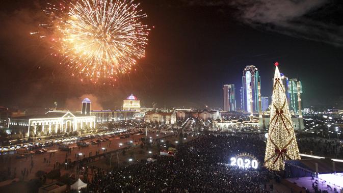 Kembang api meledak di atas pohon Natal dan gedung pencakar langit selama perayaan Tahun Baru di Grozny, Rusia, Rabu (1/1/2020). (AP Photo/Musa Sadulayev)