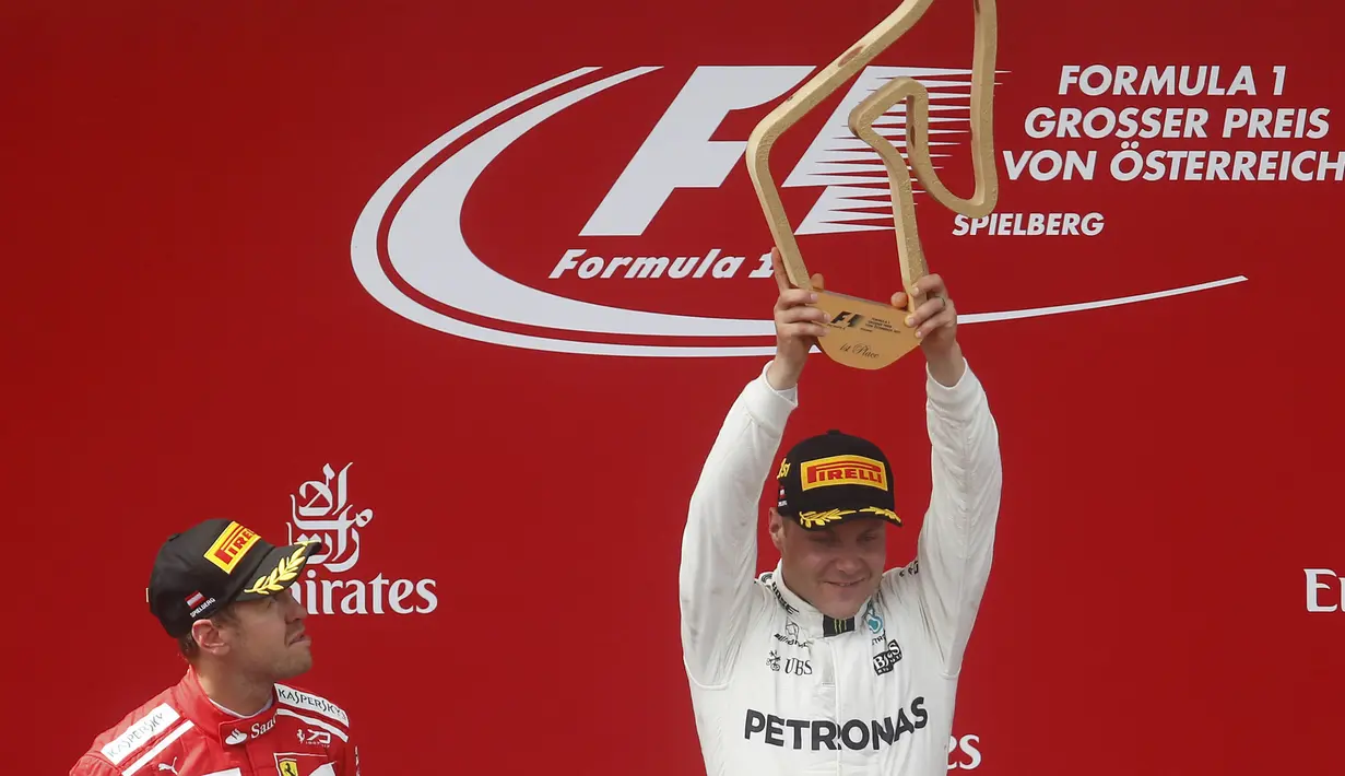 Pebalap Mercedes, Valtteri Bottas, mengangkat trofi usai berhasil menjuarai F1 GP Austria di Sirkuit Red Bull Ring, Minggu (9/7/2017). Valtteri Bottas menjadi yang tercepat dengan catatan waktu 1 jam 21 menit 48,527 detik. (AP/Darko Bandic)